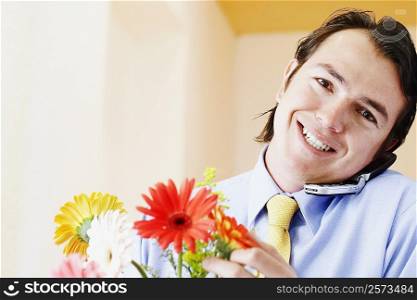Portrait of a businessman holding flowers and talking on a mobile phone