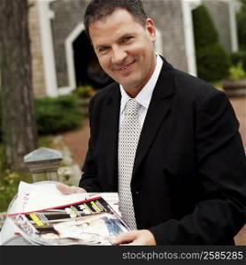 Portrait of a businessman holding magazines and smiling