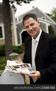 Portrait of a businessman holding magazines and smiling