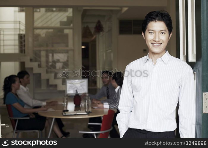 Portrait of a businessman leaning against a door and smiling