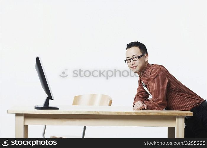 Portrait of a businessman leaning against a table and smiling