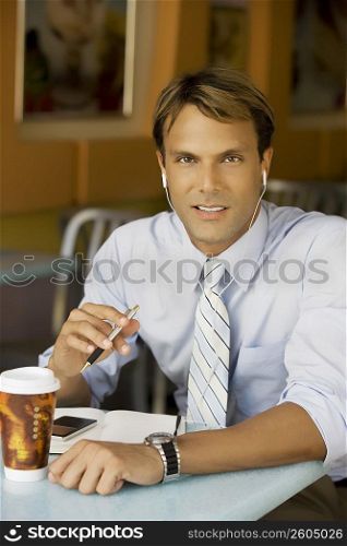 Portrait of a businessman listening to an MP3 player in a cafe
