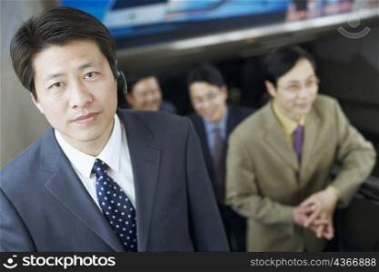 Portrait of a businessman on an escalator wearing a hands free device