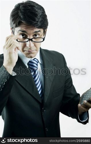 Portrait of a businessman peeking over his eyeglasses and holding a calculator