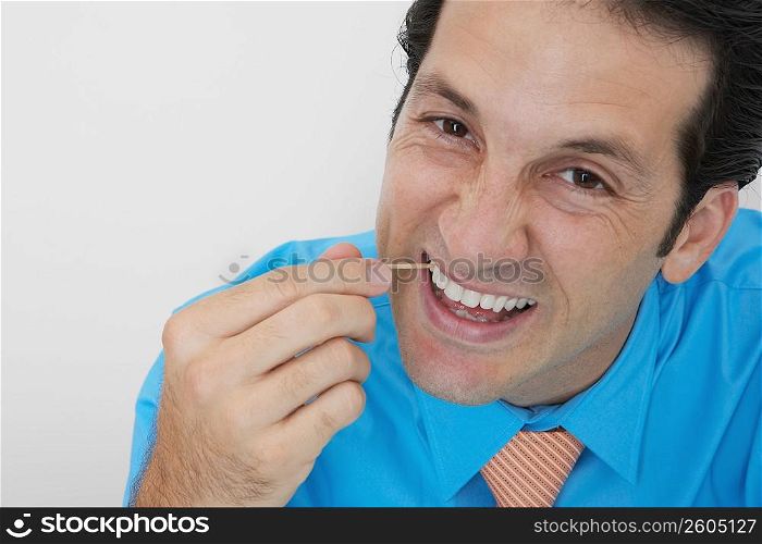 Portrait of a businessman picking his teeth in an office