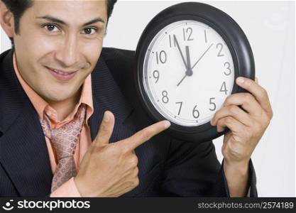 Portrait of a businessman pointing at a clock