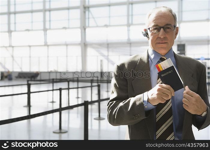 Portrait of a businessman putting a passport with an airplane ticket in his coat&acute;s pocket