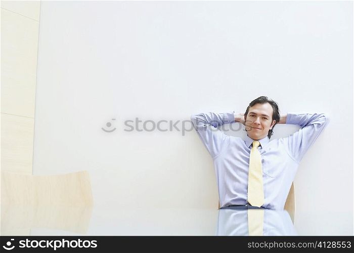 Portrait of a businessman relaxing with his hands behind his head in an office