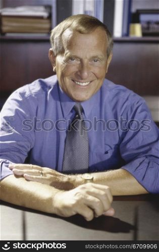 Portrait of a businessman seated behind an office desk smiling