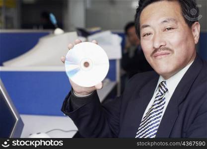 Portrait of a businessman showing a CD