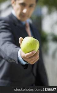 Portrait of a businessman showing a granny smith apple