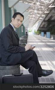 Portrait of a businessman sitting and using a palmtop