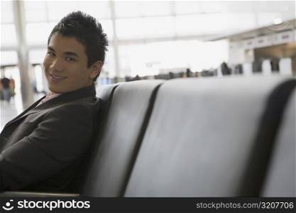 Portrait of a businessman sitting at an airport and smiling