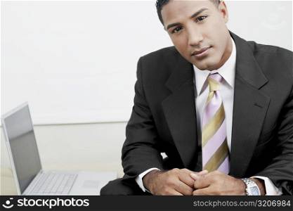 Portrait of a businessman sitting beside a laptop