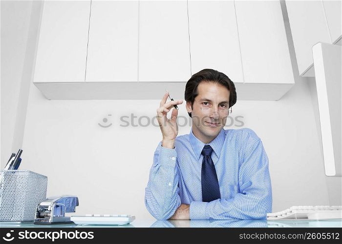 Portrait of a businessman sitting in an office and holding a pen