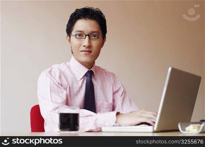 Portrait of a businessman sitting in an office and using a laptop