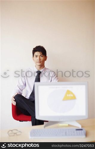 Portrait of a businessman sitting in an office in front of a model of a computer monitor