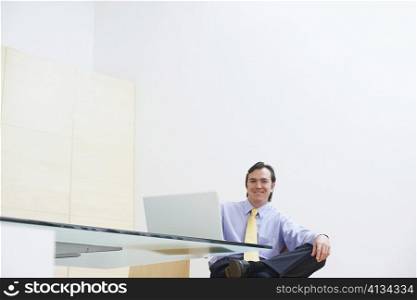 Portrait of a businessman sitting in an office with a laptop in front of him