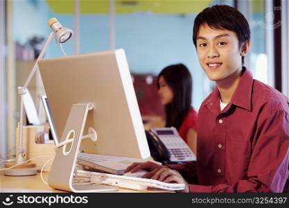 Portrait of a businessman sitting in front of a computer in an office and smiling