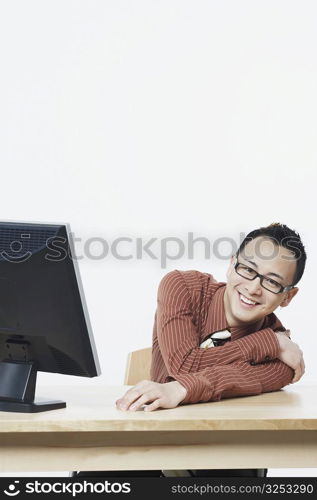 Portrait of a businessman sitting in front of a flat screen monitor