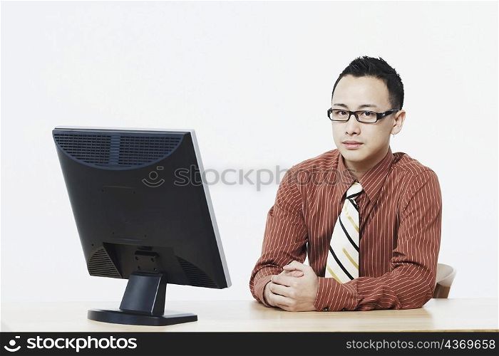 Portrait of a businessman sitting in front of a flat screen monitor
