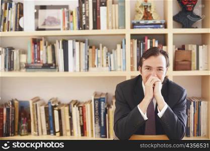 Portrait of a businessman sitting in front of book shelves