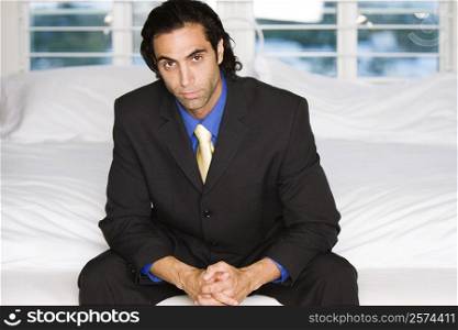 Portrait of a businessman sitting on a bed