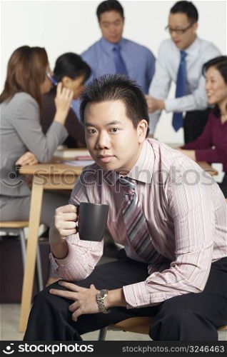 Portrait of a businessman sitting on a chair holding a coffee cup