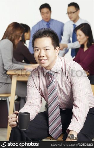 Portrait of a businessman sitting on a chair holding a coffee cup