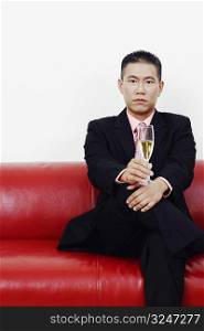 Portrait of a businessman sitting on a couch and holding a champagne flute