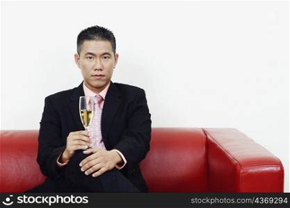 Portrait of a businessman sitting on a couch and holding a champagne flute