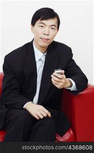 Portrait of a businessman sitting on a couch and holding a mobile phone