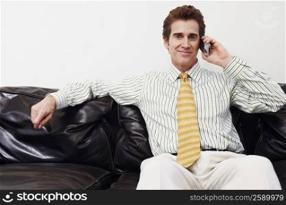 Portrait of a businessman sitting on a couch and talking on a mobile phone