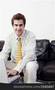 Portrait of a businessman sitting on a couch and using a laptop