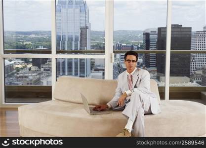 Portrait of a businessman sitting on a couch and using a laptop