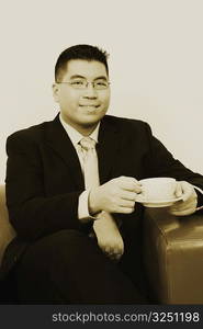 Portrait of a businessman sitting on a couch with a cup of tea and smiling