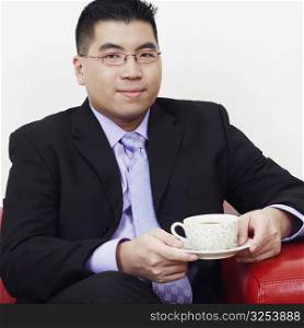 Portrait of a businessman sitting on a couch with a cup of tea and smiling