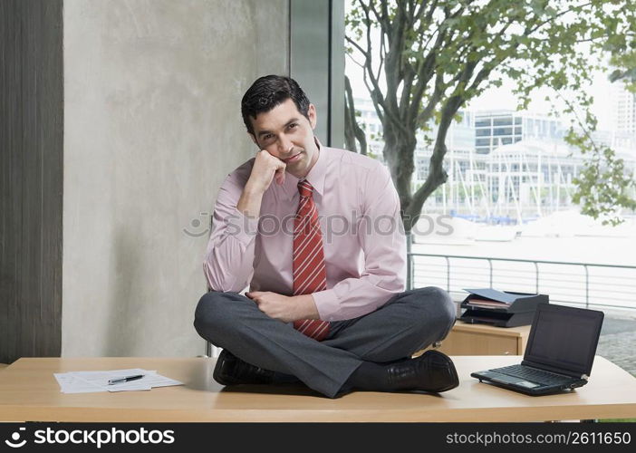 Portrait of a businessman sitting on a desk