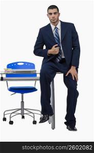 Portrait of a businessman sitting on a desk in an office