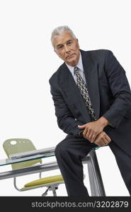 Portrait of a businessman sitting on a desk in an office