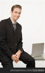 Portrait of a businessman sitting on a desk in an office