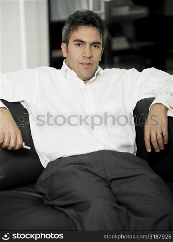 Portrait of a businessman sitting on the couch and holding a mobile phone
