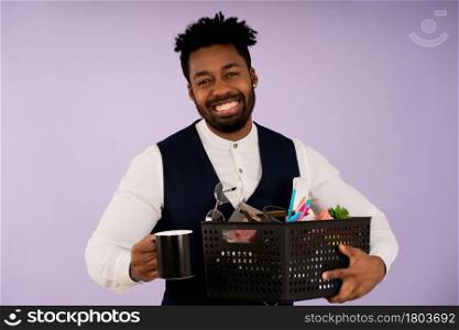 Portrait of a businessman smiling while holding a box with personal items for the office. Business concept.