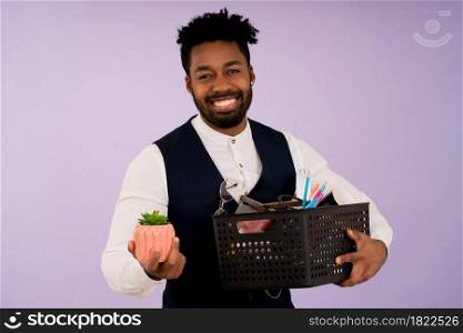 Portrait of a businessman smiling while holding a box with personal items for the office. Business concept.