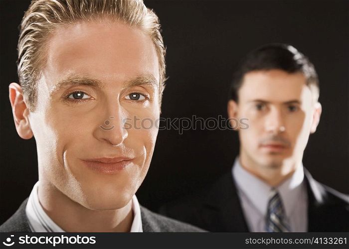 Portrait of a businessman smiling with a businessman behind him