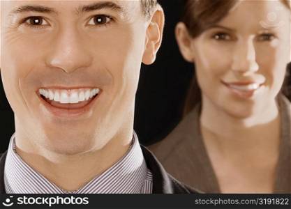 Portrait of a businessman smiling with a businesswoman behind her