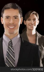 Portrait of a businessman smiling with a businesswoman standing behind him