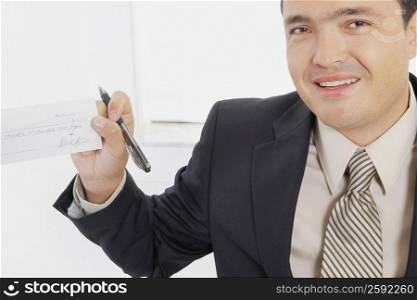 Portrait of a businessman smiling with a pen and a check