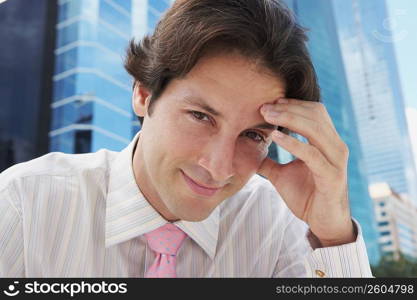 Portrait of a businessman smiling with his hand on his forehead