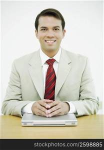 Portrait of a businessman smiling with his hands on a laptop